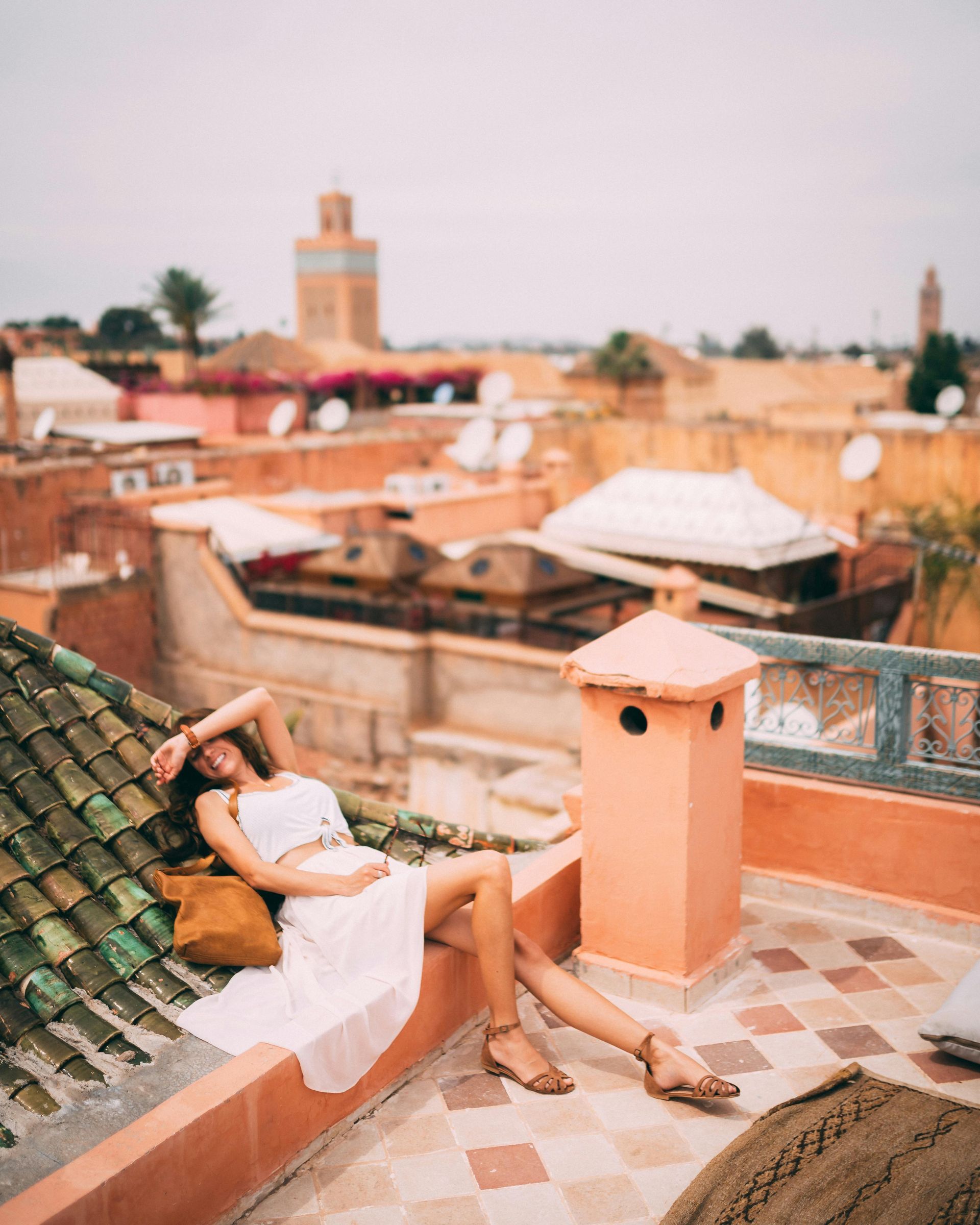 A woman in a white dress is sitting on the roof of a building.