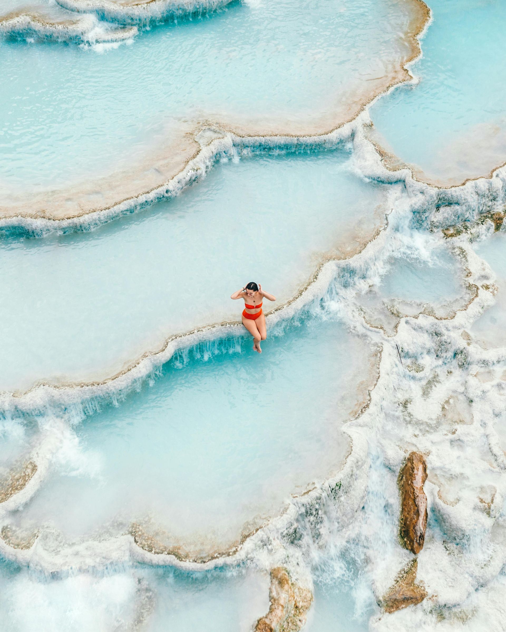 An aerial view of a woman swimming in a pool of water.
