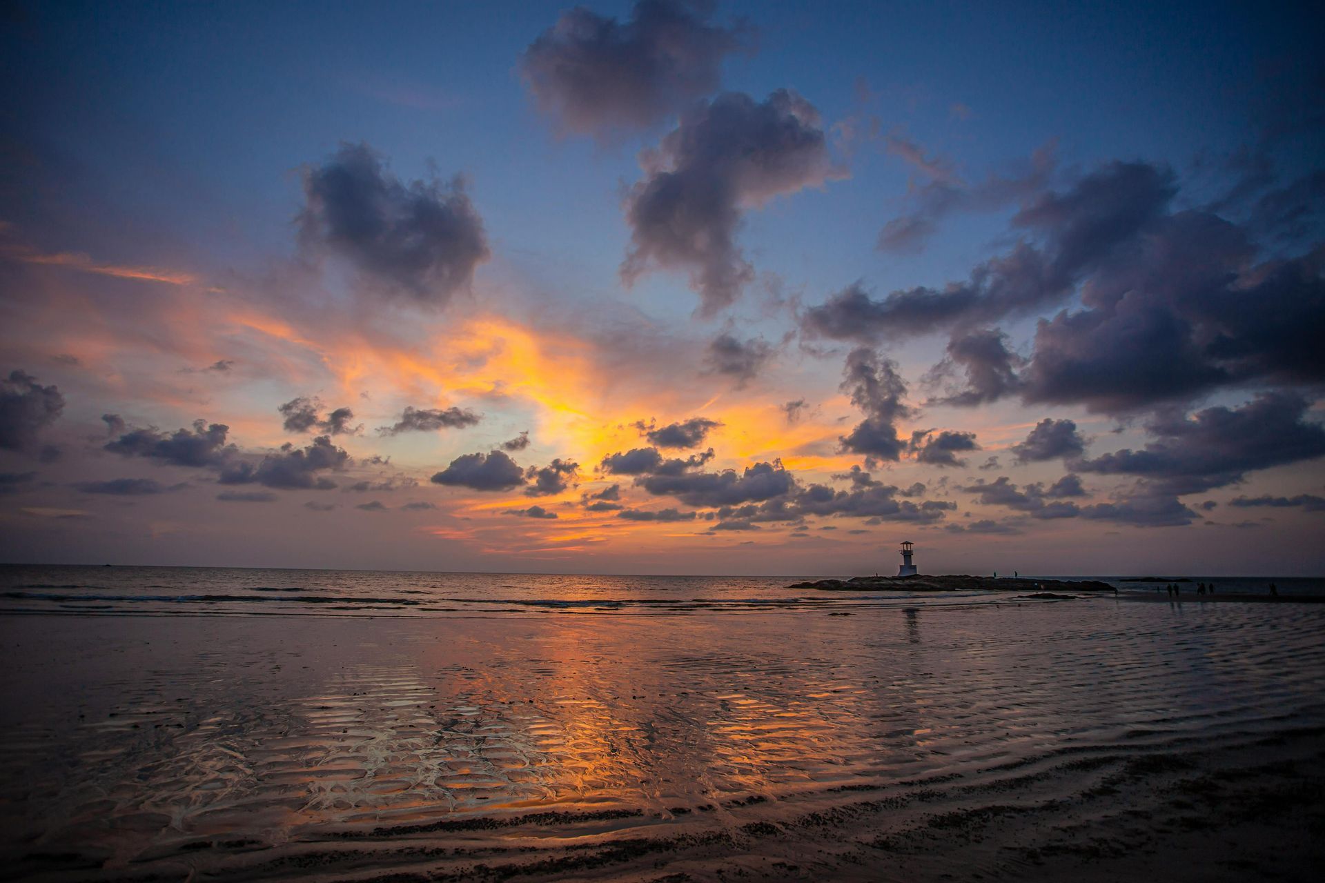 A sunset over a body of water with a lighthouse in the distance.