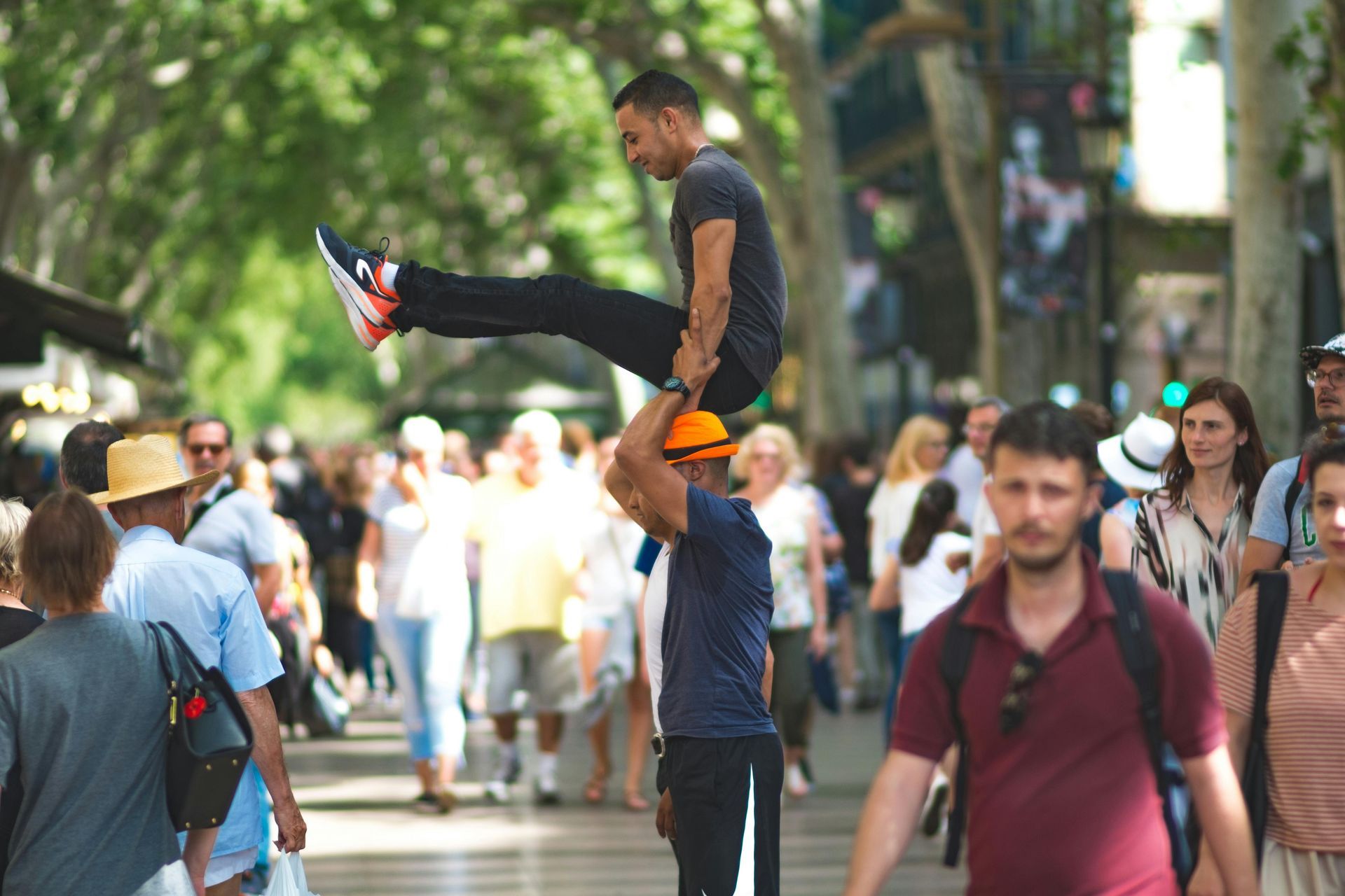 A man is carrying another man on his shoulders while walking down a crowded street.