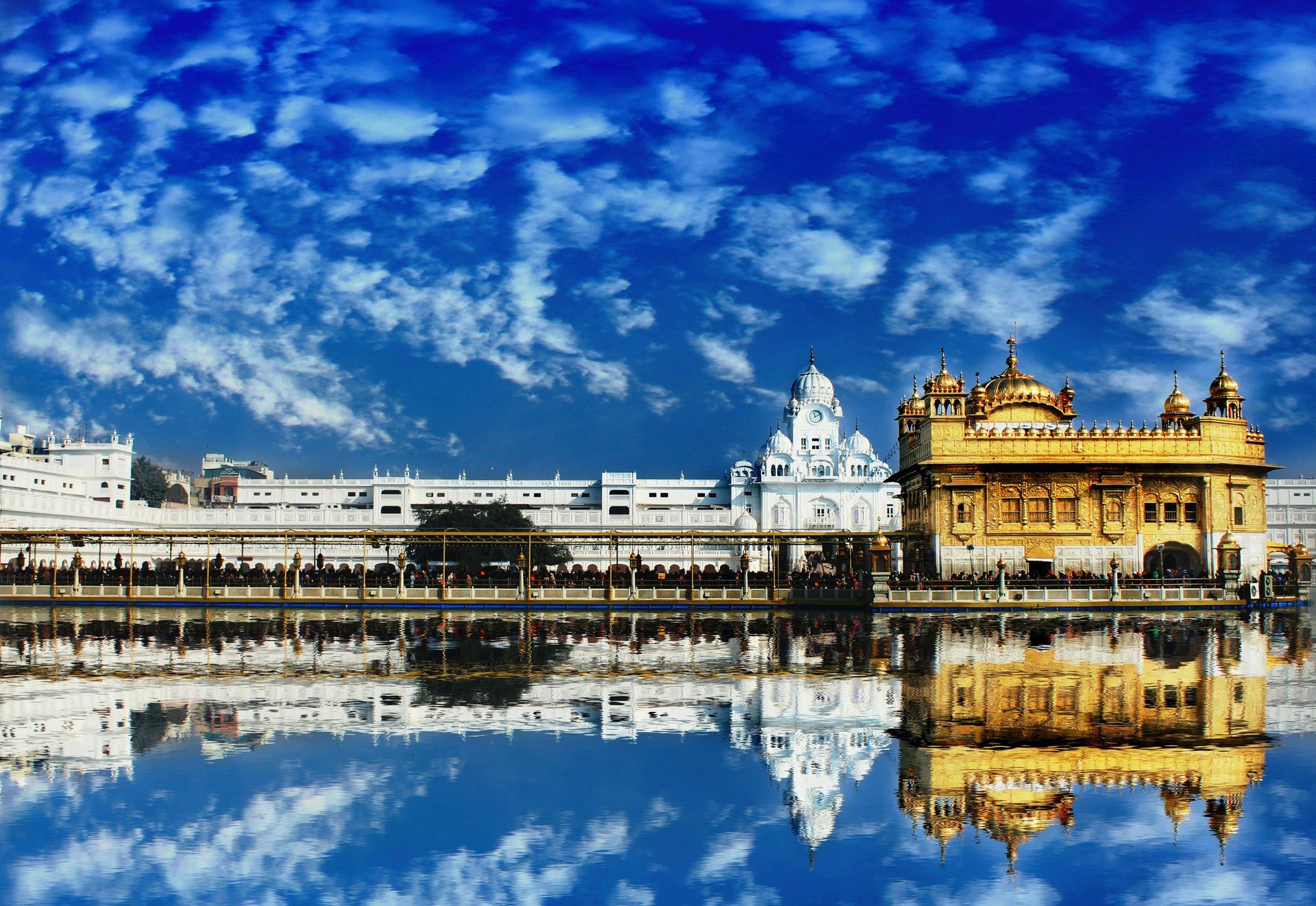The golden temple is reflected in the water on a sunny day.