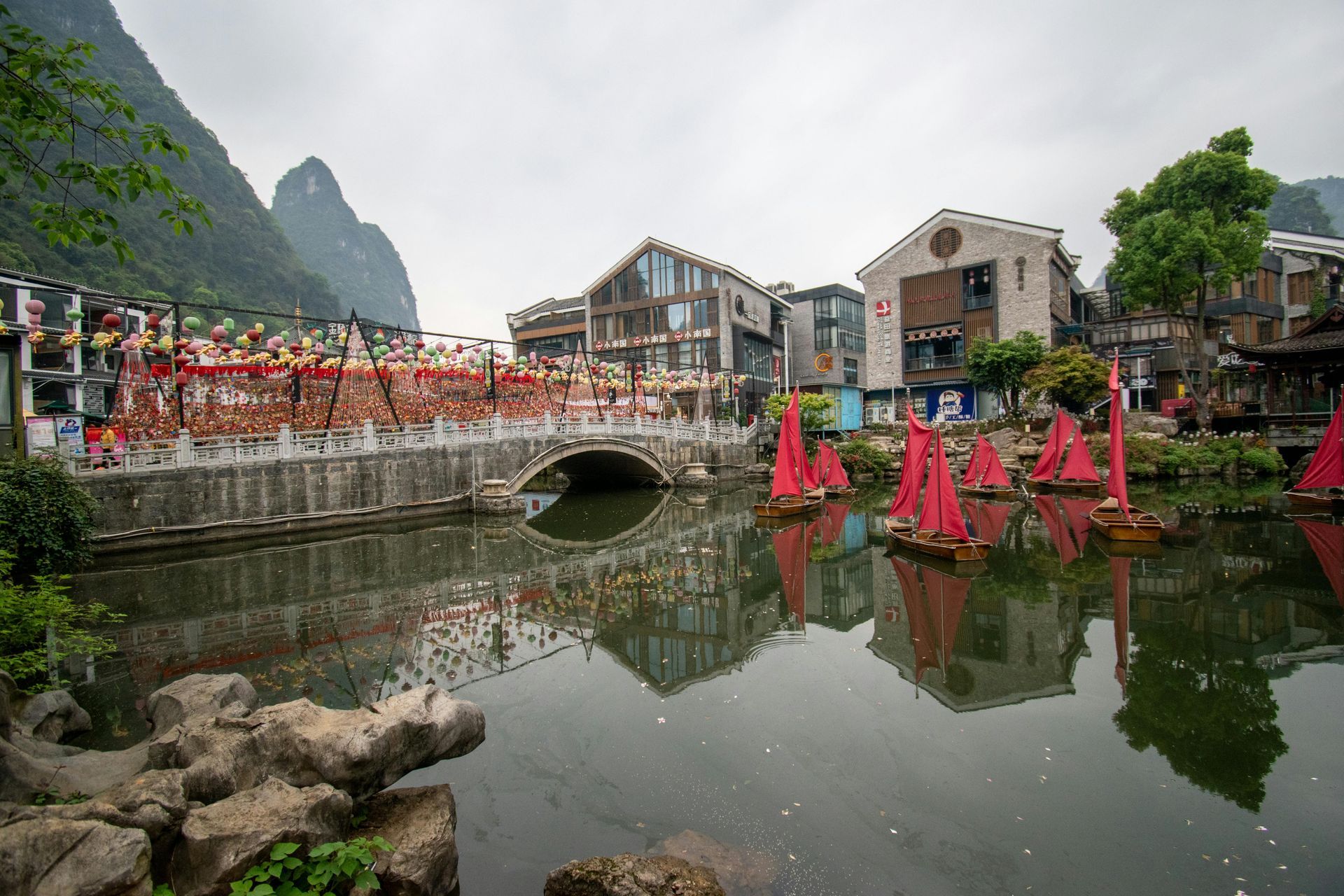 A group of red sailboats are floating on top of a body of water.