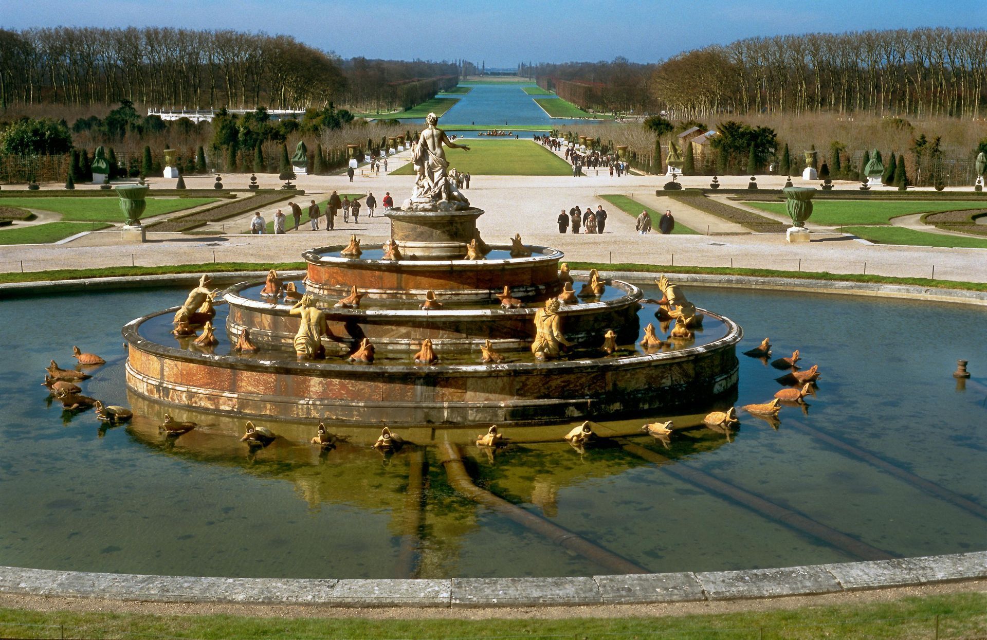 A fountain in a park with ducks swimming in it