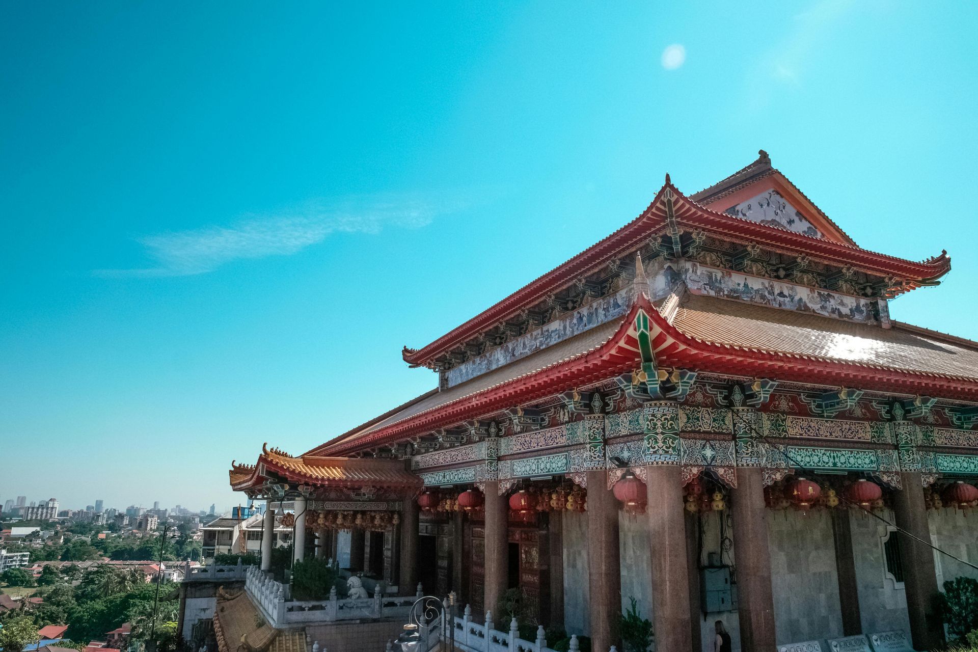 A large chinese building with a red roof and a blue sky in the background.
