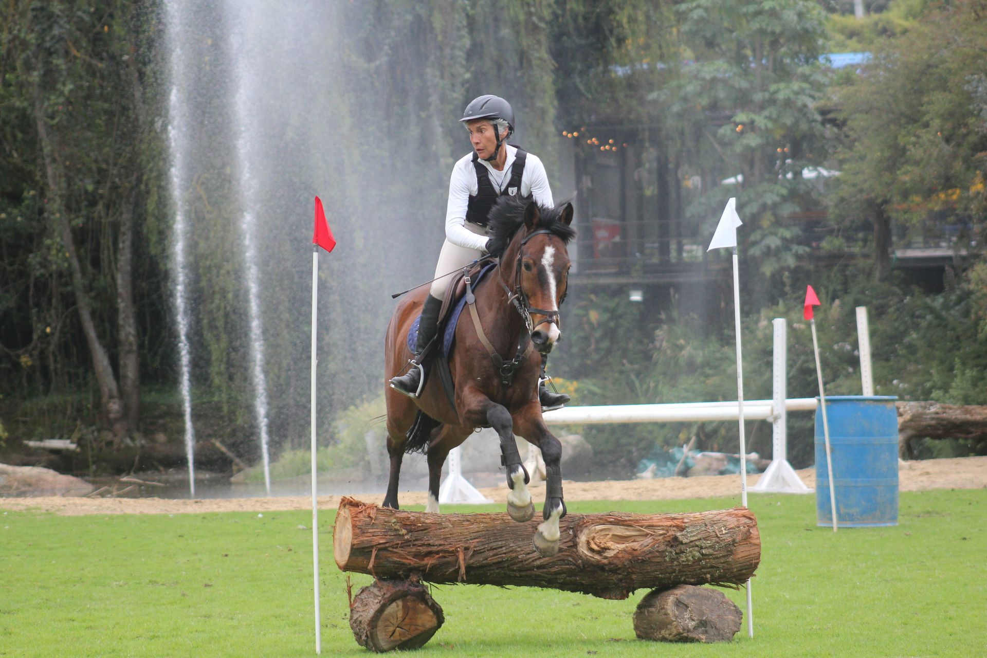 A man is riding a horse over a log.