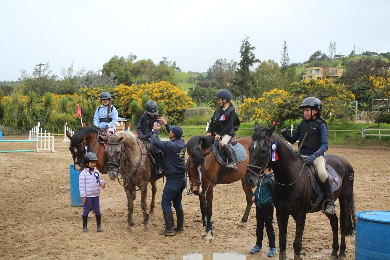 A group of people are riding horses in a dirt field.