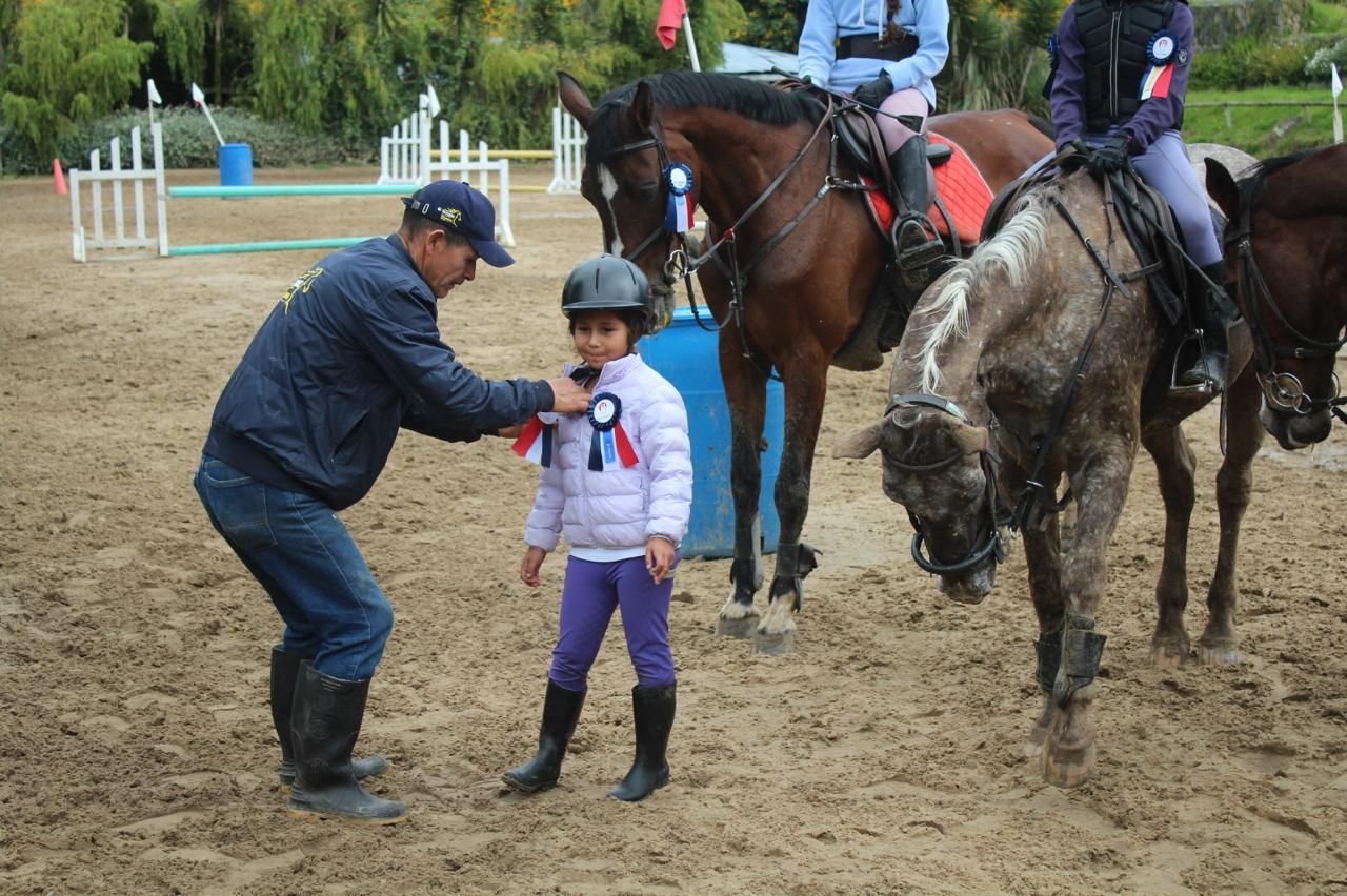 A man is putting a ribbon on a little girl 's jacket