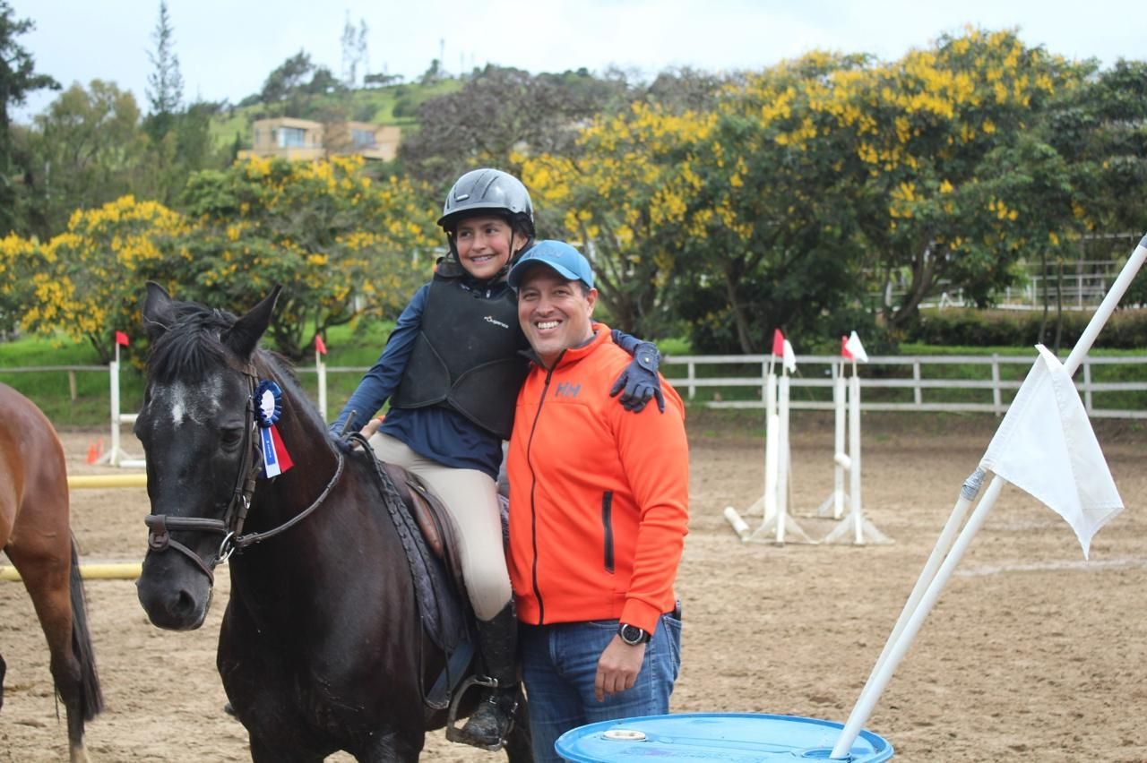 A man is standing next to a girl riding a horse