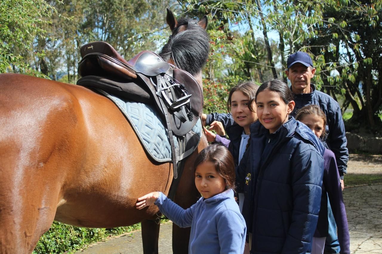 A group of people standing next to a horse with a saddle on it.