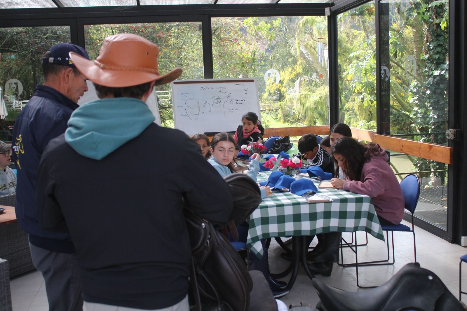 A group of people are sitting at a table with a white board in the background