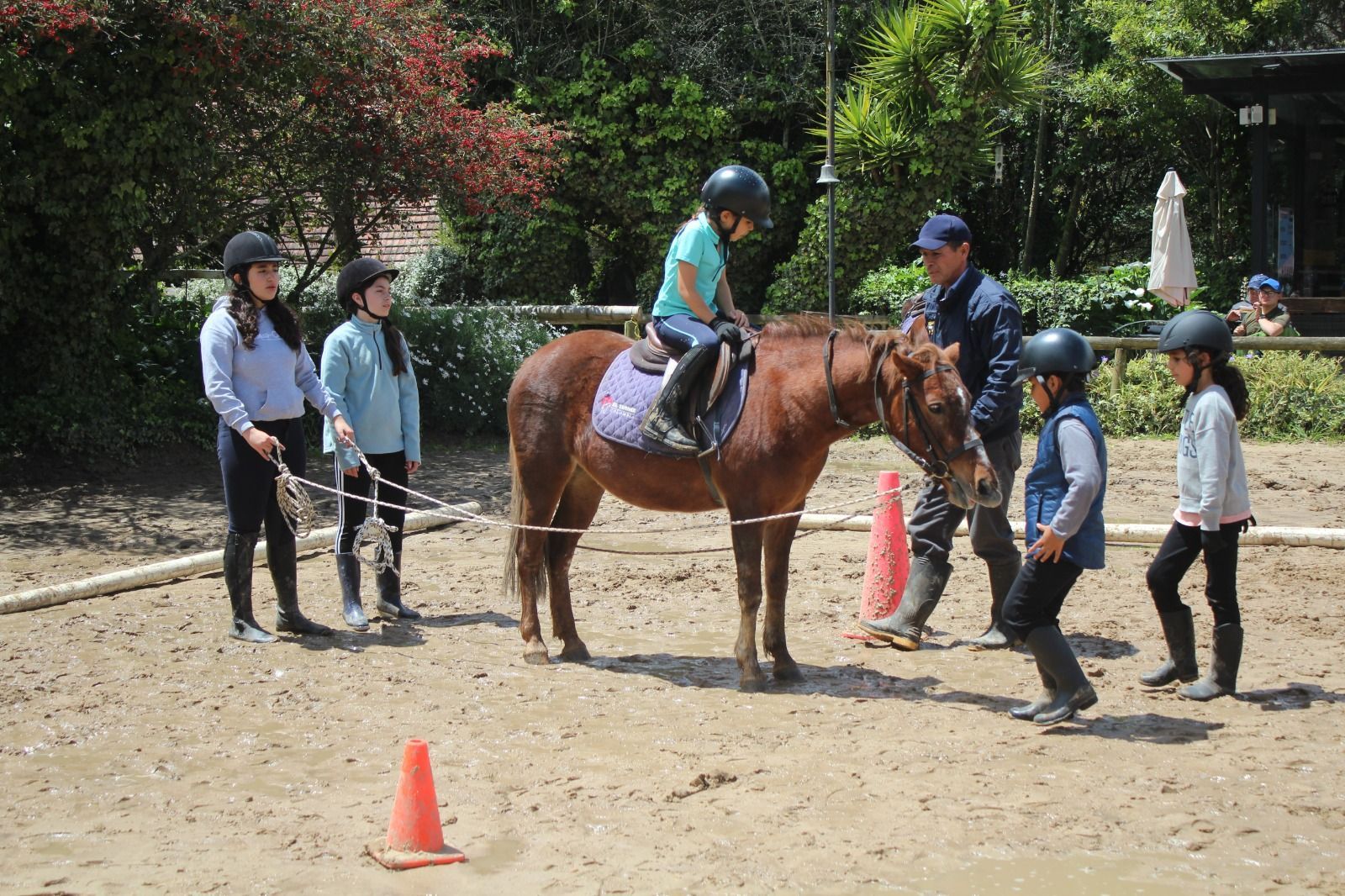 A group of children are riding horses in a dirt field.