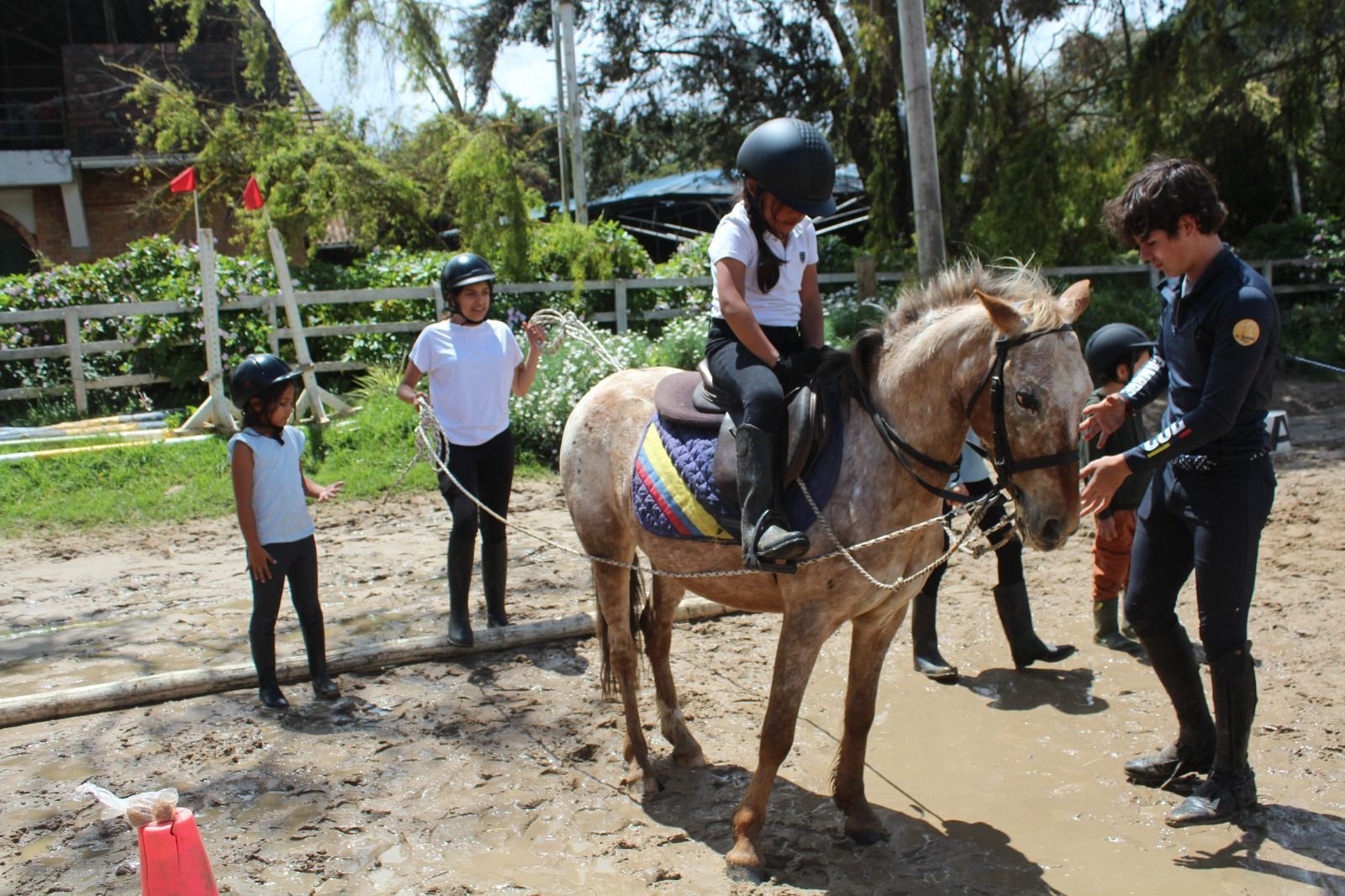 A group of people are riding horses in a dirt field.