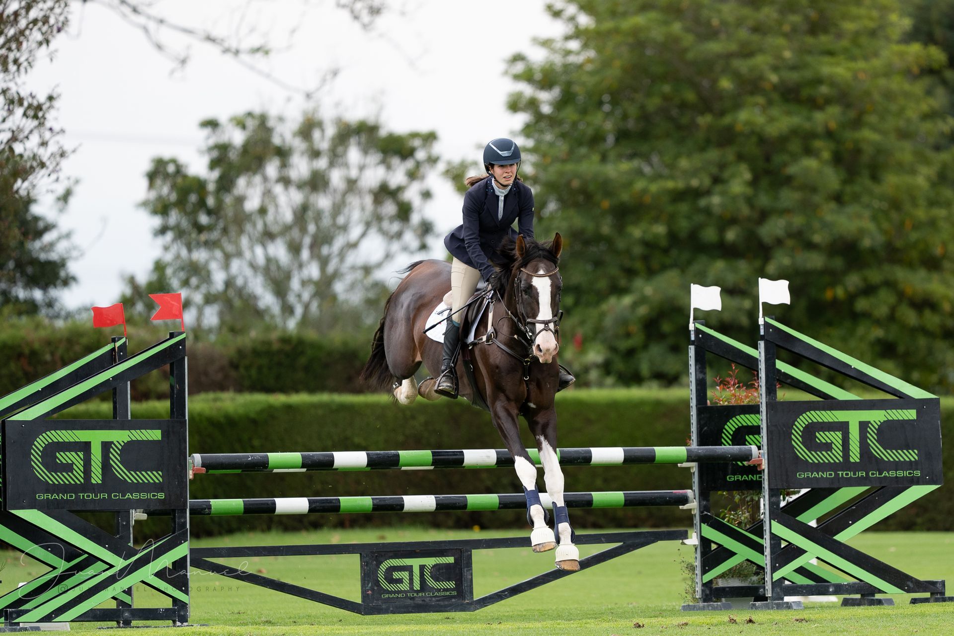 A woman is riding a horse over a jump.