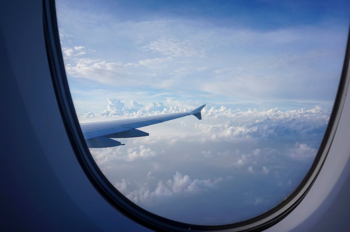 The wing of an airplane is visible through the window of an airplane.