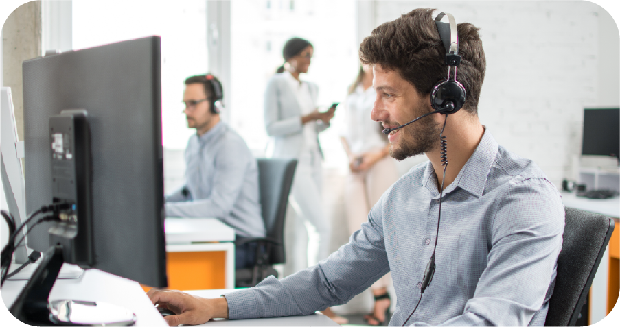 A man wearing a headset is sitting in front of a computer.