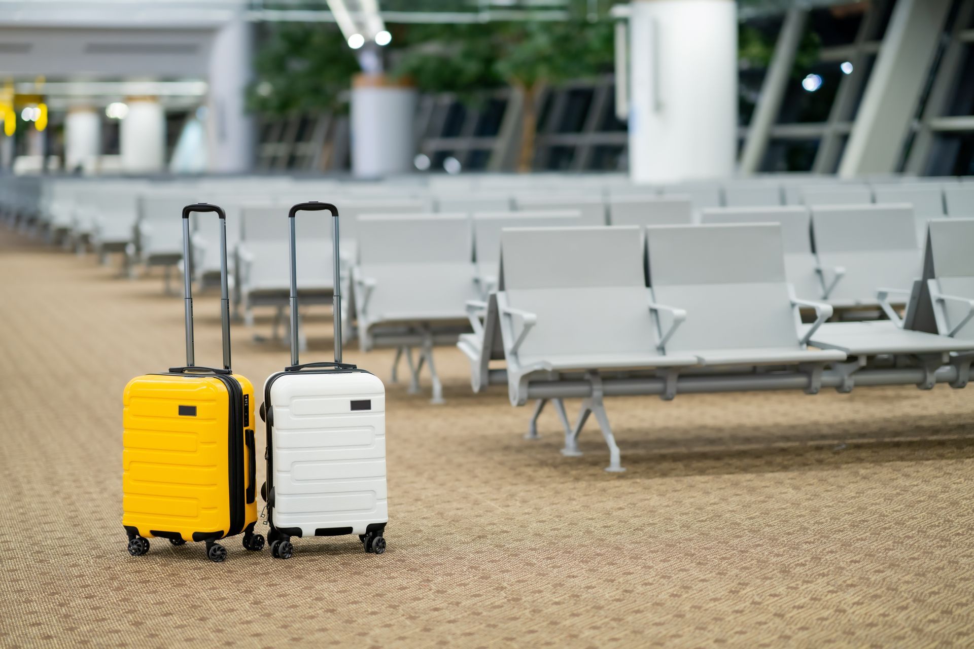 Two suitcases are sitting next to each other in an airport waiting area.