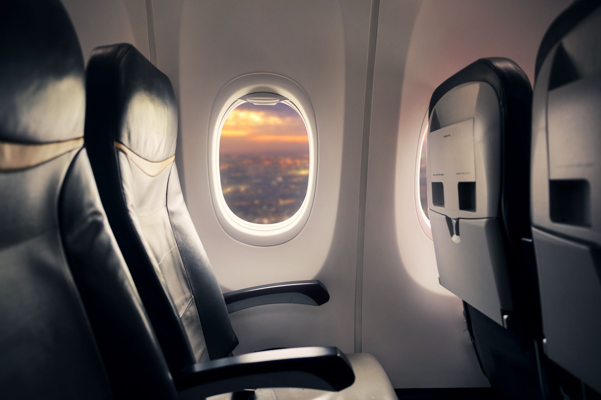 The inside of an airplane looking out the window at the sunset