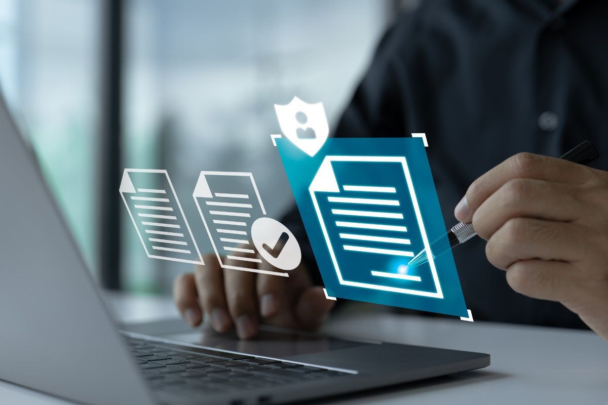 A person is signing a document on a laptop computer