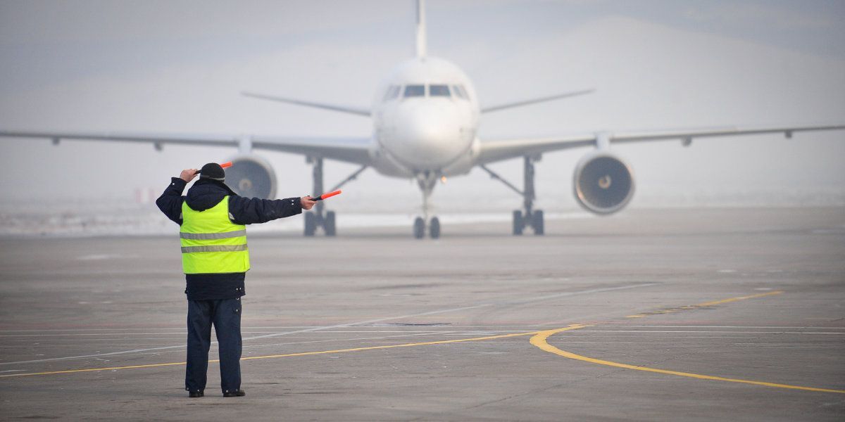 A man in a yellow vest is standing in front of an airplane