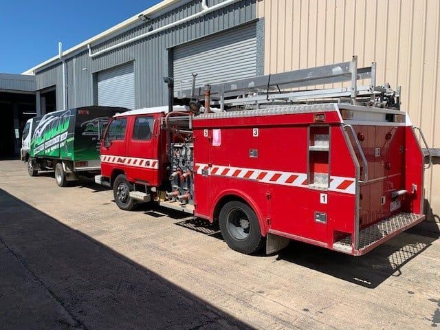 Red Fire Truck With White Stripes Parked Outside a Building — A.M.D. Automotive Services in Mackay, QLD