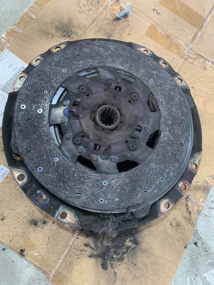 Worn Clutch Disc With Visible Wear and Tear, Covered in Dark Debris — A.M.D. Automotive Services in Mackay, QLD