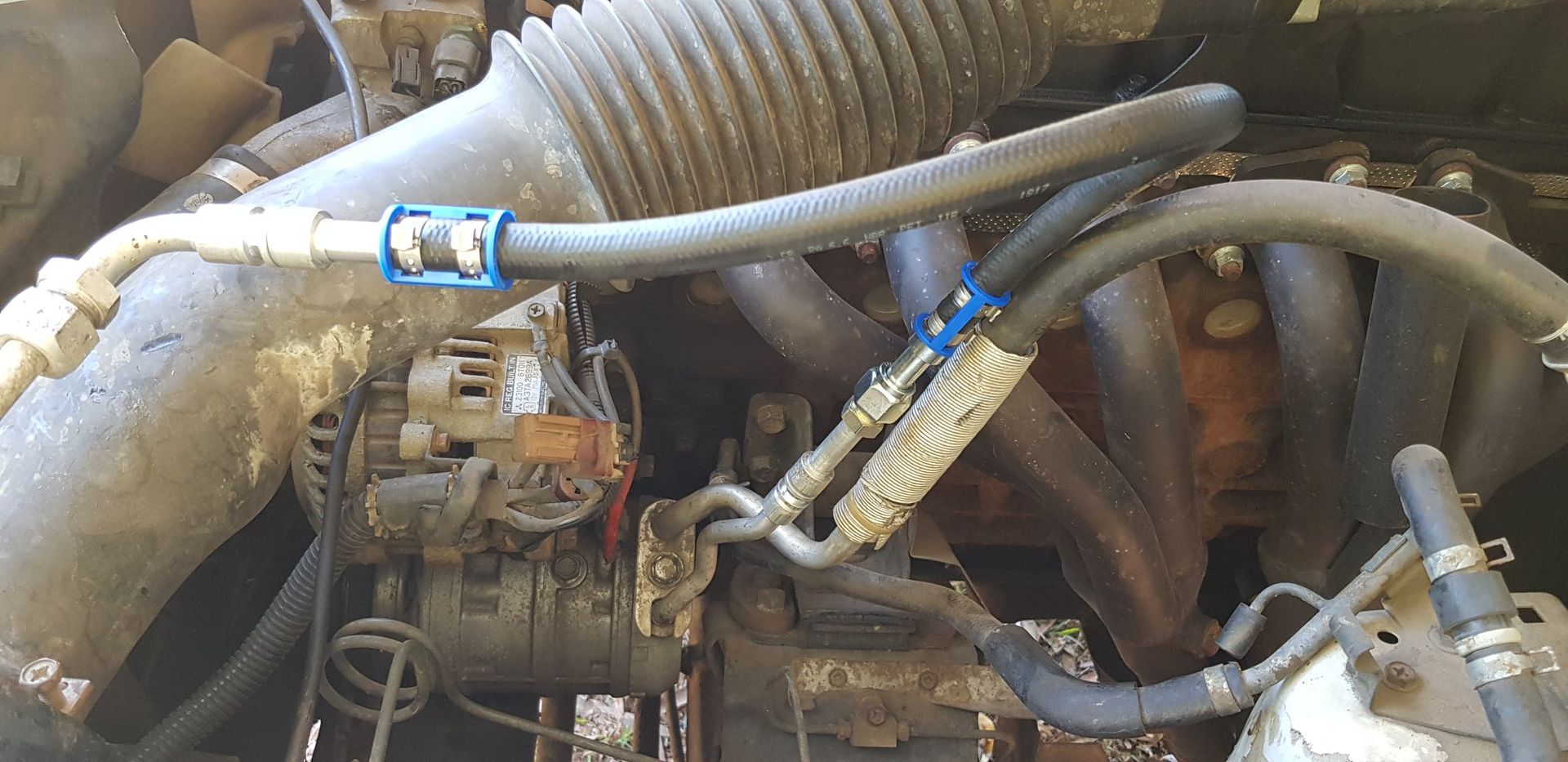 Engine Bay With Hoses, Tubes, and a Belt, Some Components Covered in Insulation — A.M.D. Automotive Services in Mackay, QLD