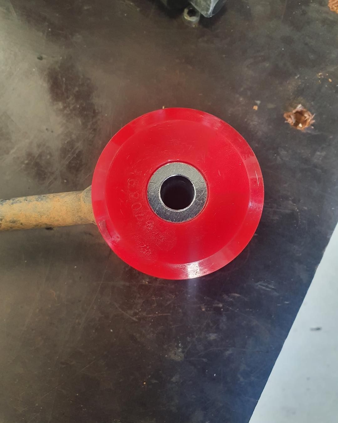 Red Polyurethane Bushing With a Metal Sleeve on a Workbench — A.M.D. Automotive Services in Moranbah, QLD