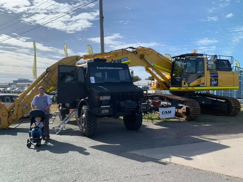 A Man and a Child in a Stroller Pose Next to a Black Truck — A.M.D. Automotive Services in Mackay, QLD