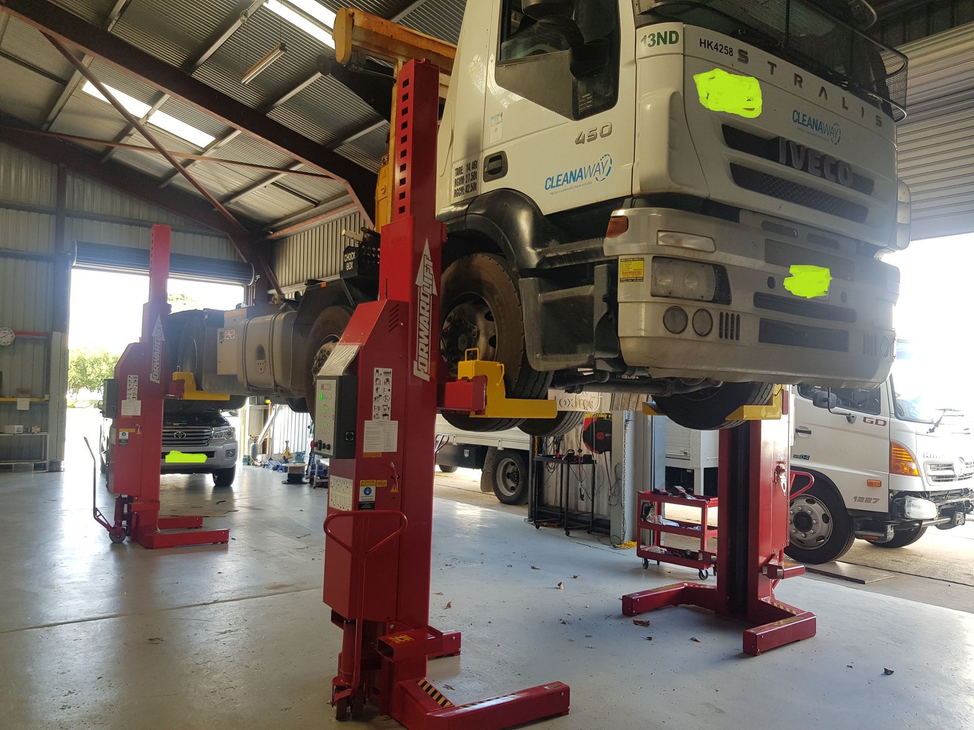 Truck Lifted on Red Hydraulic Lifts in a Garage — A.M.D. Automotive Services in Mackay, QLD