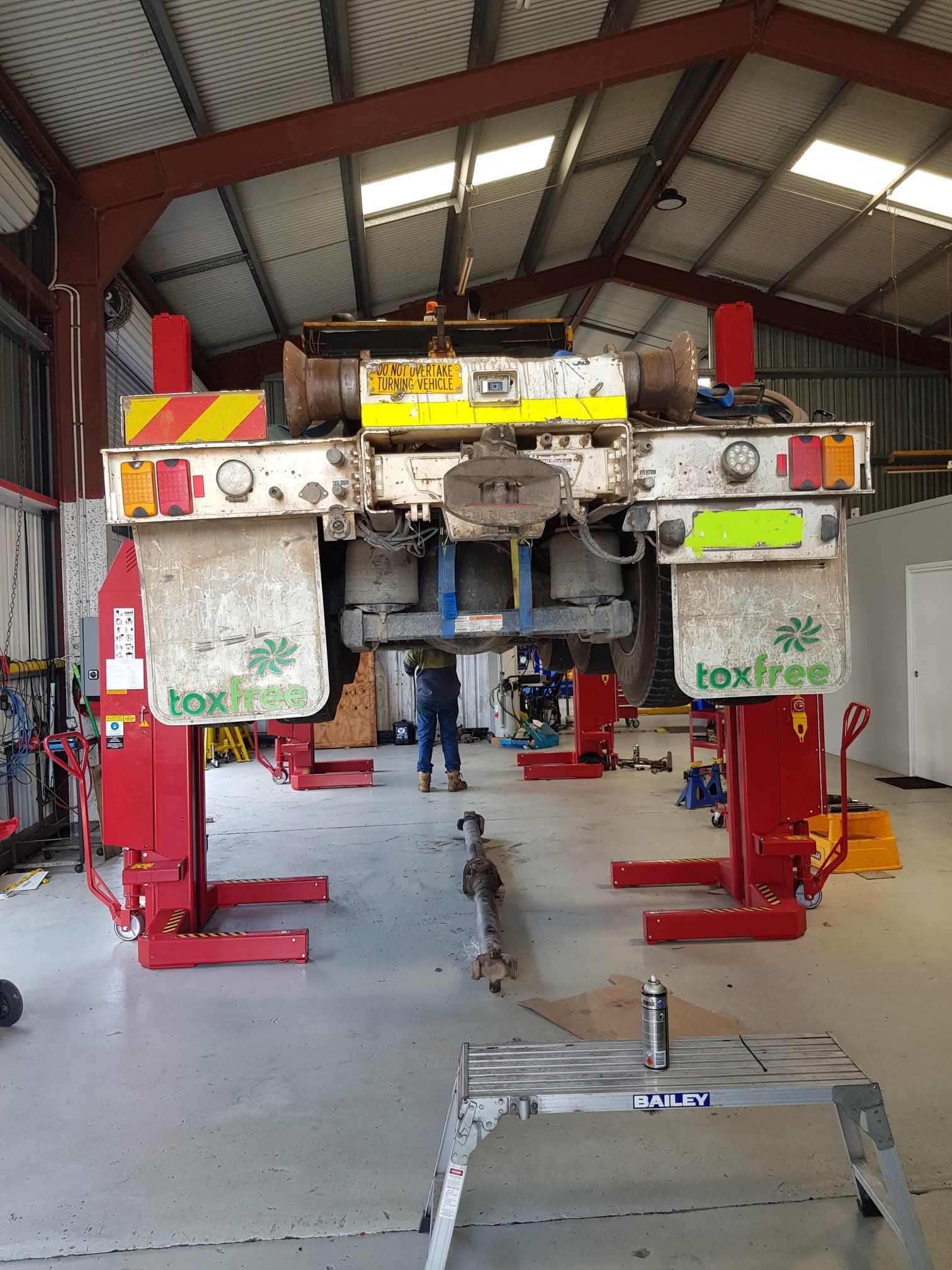 A Semi-truck Chassis is Raised on Red Lifts in a Garage — A.M.D. Automotive Services in Mackay, QLD