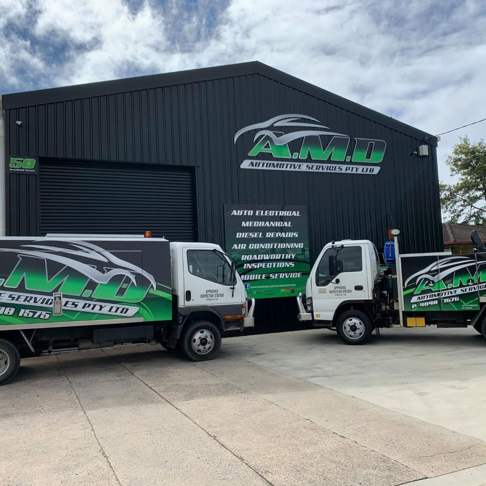 Two White Trucks Parked in Front of a Black Building — A.M.D. Automotive Services in Mackay, QLD
