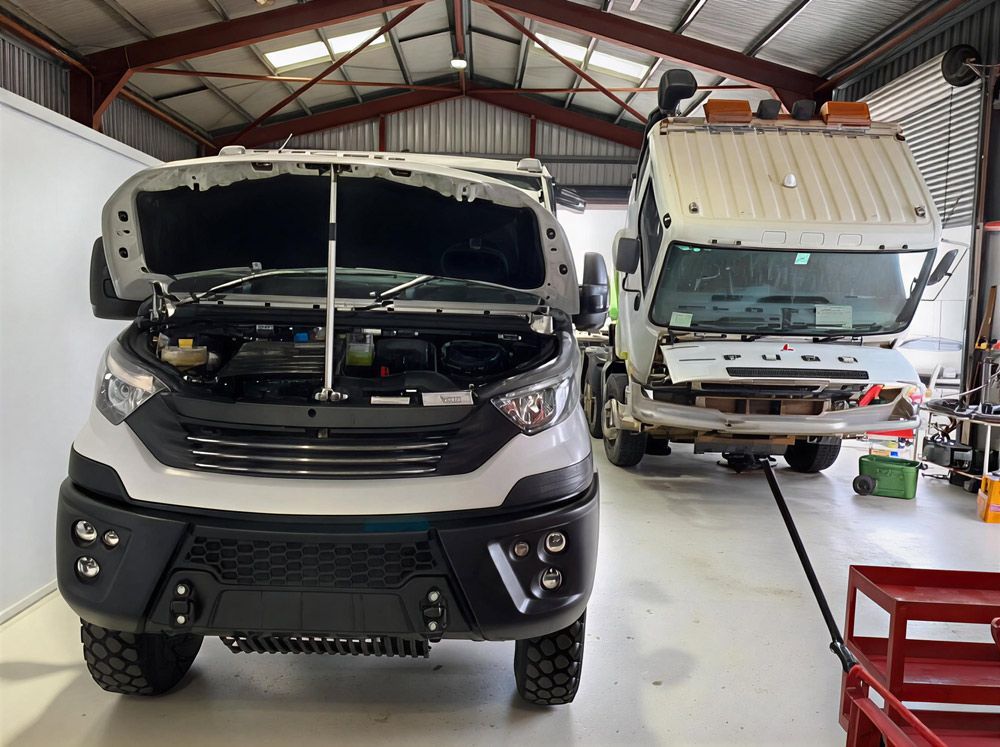 Two Trucks Inside a Workshop, One With Its Hood Open for Repair — A.M.D. Automotive Services in Mackay, QLD