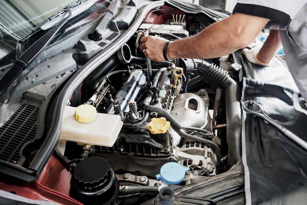 Mechanic Working on Car Engine in a Well-lit Garage, Using a Wrench — A.M.D. Automotive Services in Mackay, QLD