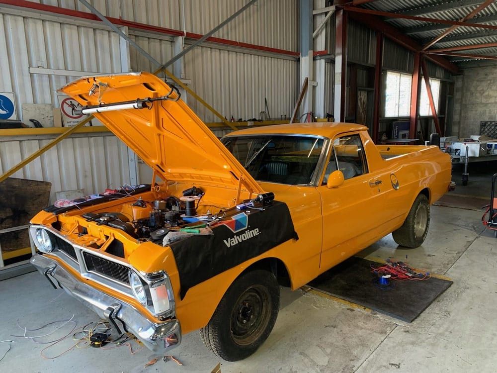 Yellow Classic Pickup Truck With Hood Open in a Workshop — A.M.D. Automotive Services in Mackay, QLD