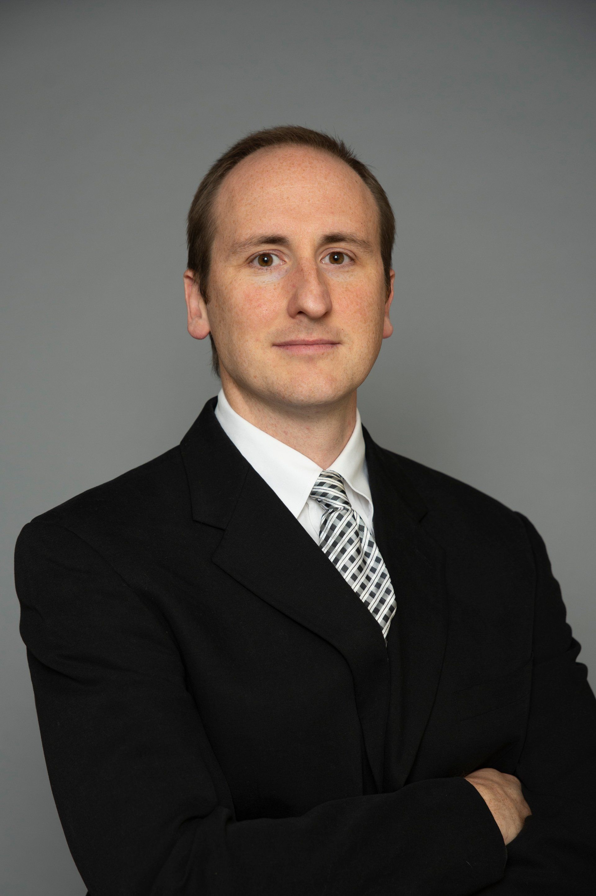 A man in a suit and tie is standing with his arms crossed.