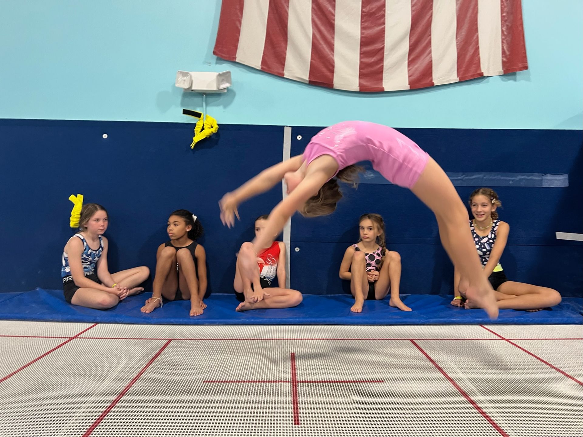 A group of young girls are doing gymnastics on a trampoline.