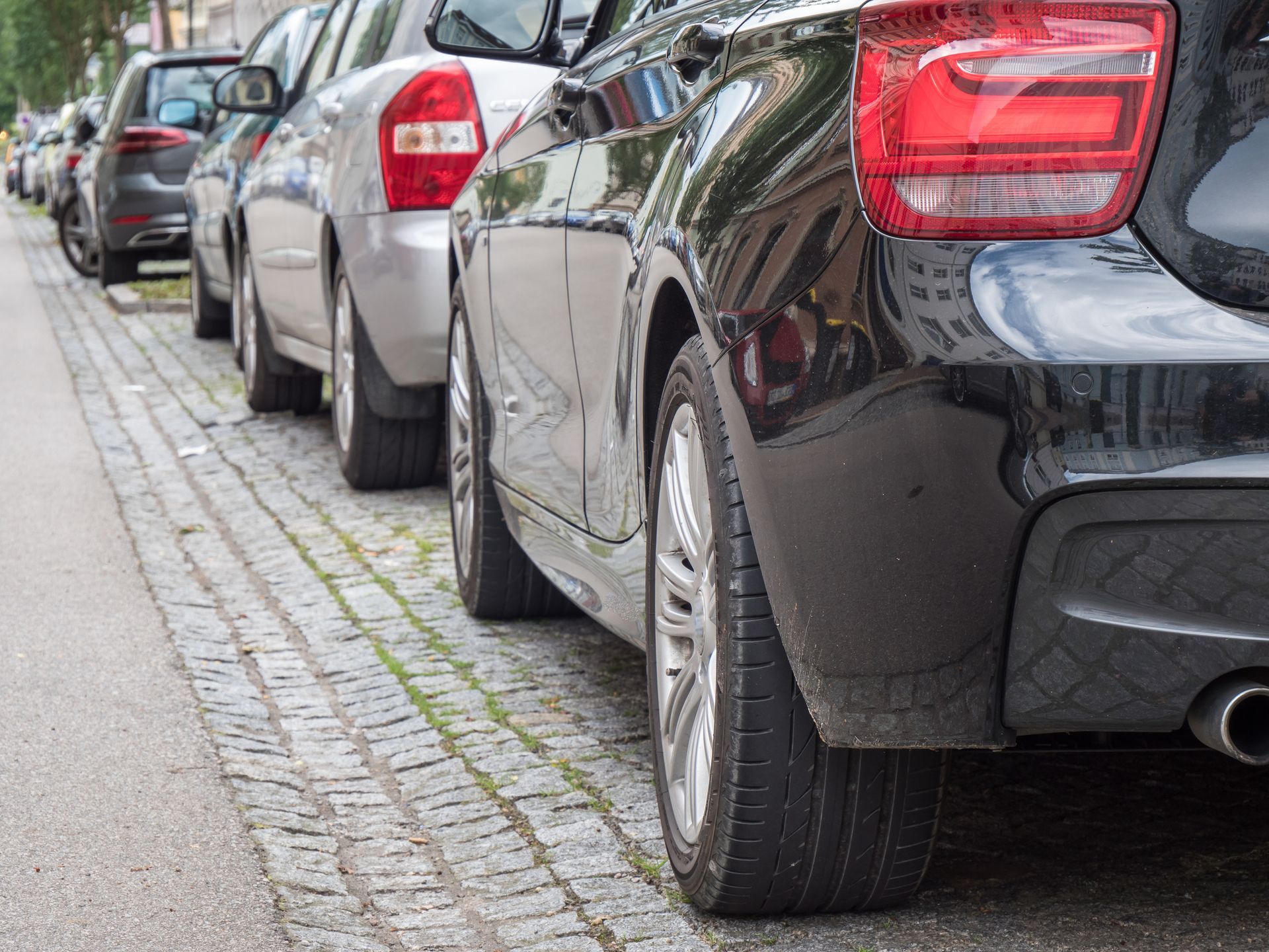 Una fila de coches están aparcados al costado de la carretera.