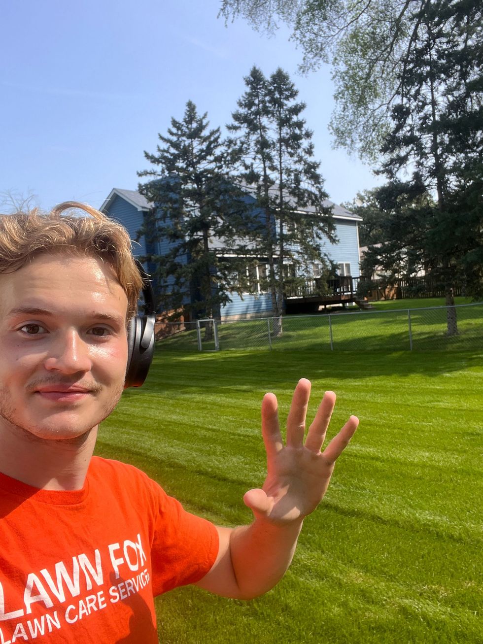 Lawn Fox Lawn Care employee standing on a lawn with a house in the background.