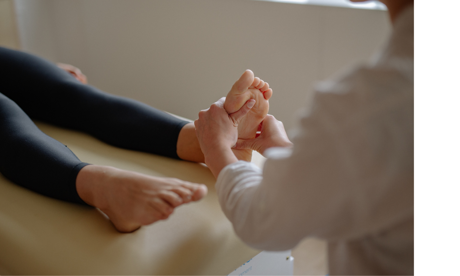 A massage therapist massages a person's foot in a treatment room.