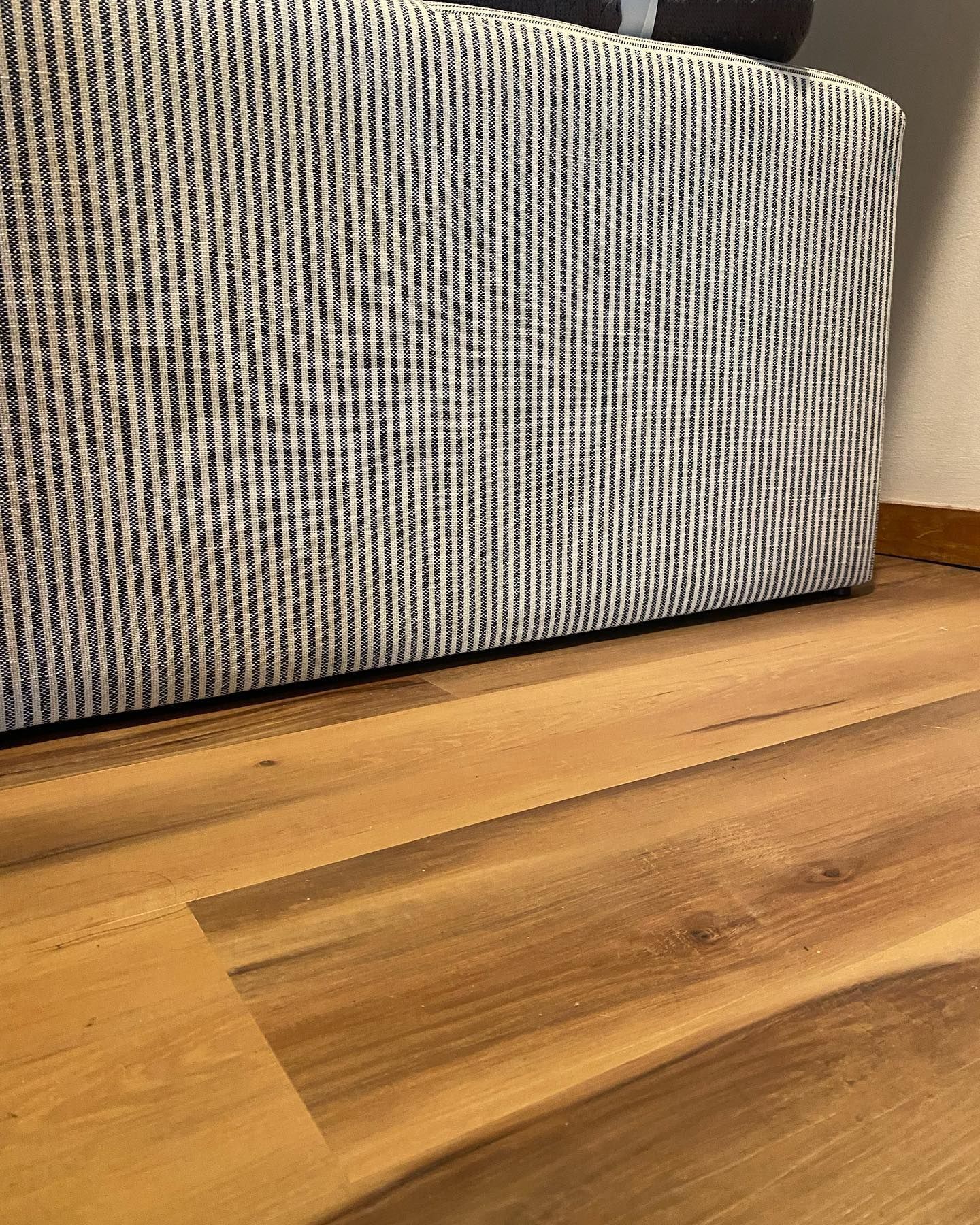 A couch is sitting on a wooden floor next to a wall.