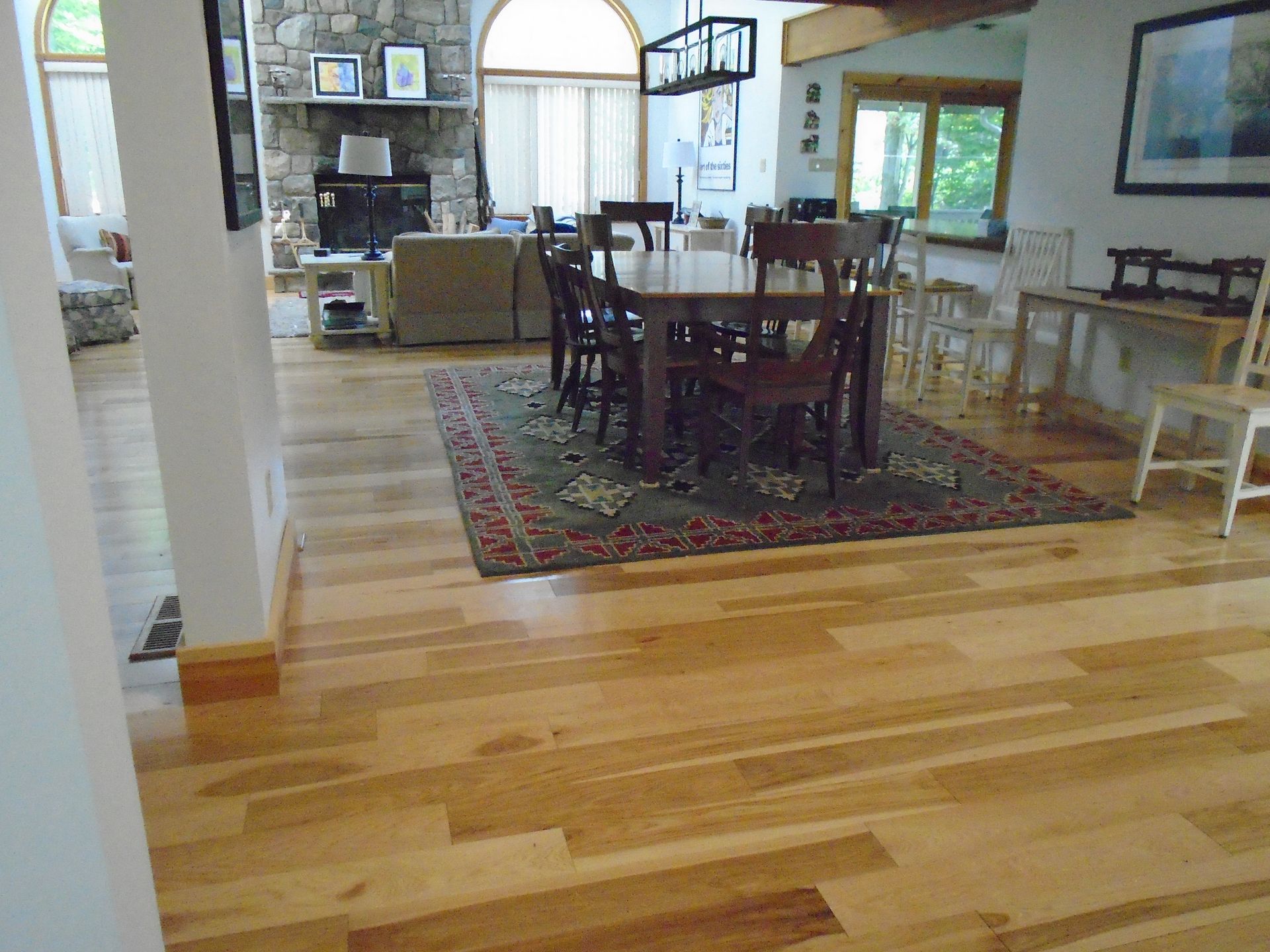 A dining room with a table and chairs and a rug on the floor