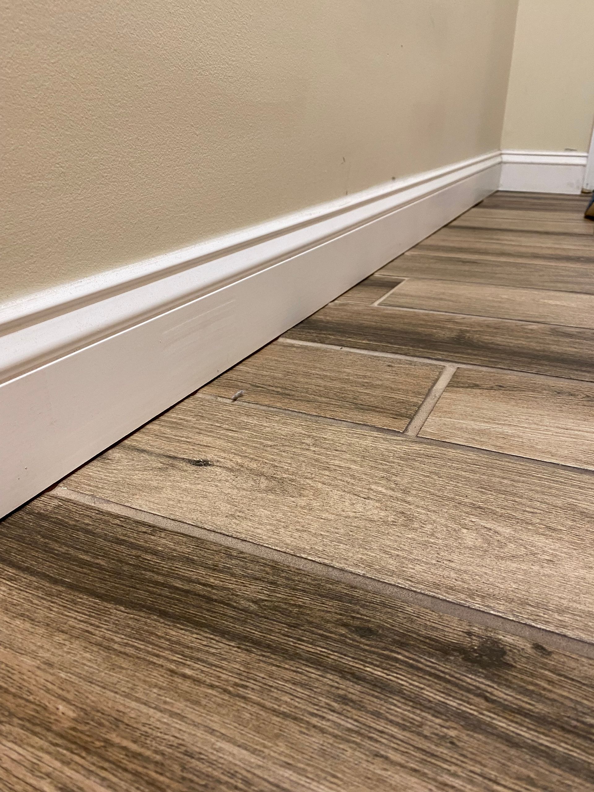 A close up of a wooden floor with a white molding.