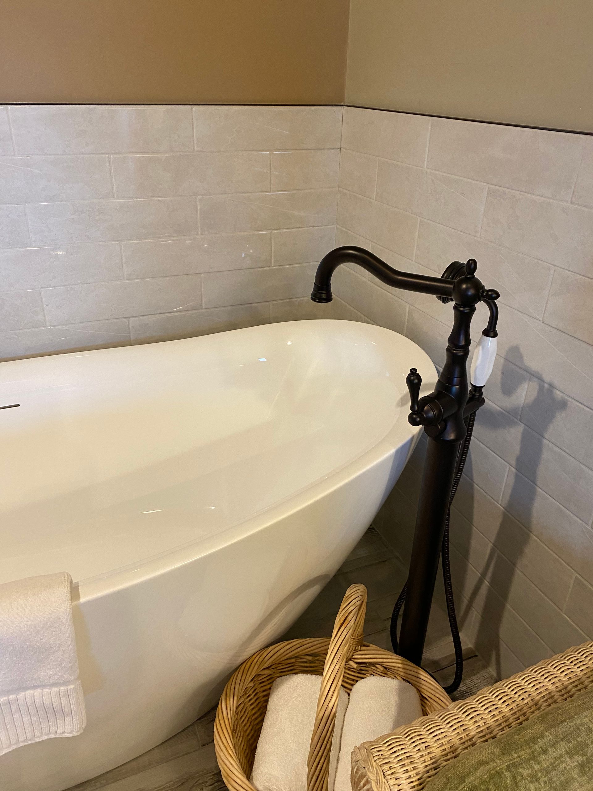 A bathroom with a bathtub and a basket of towels.