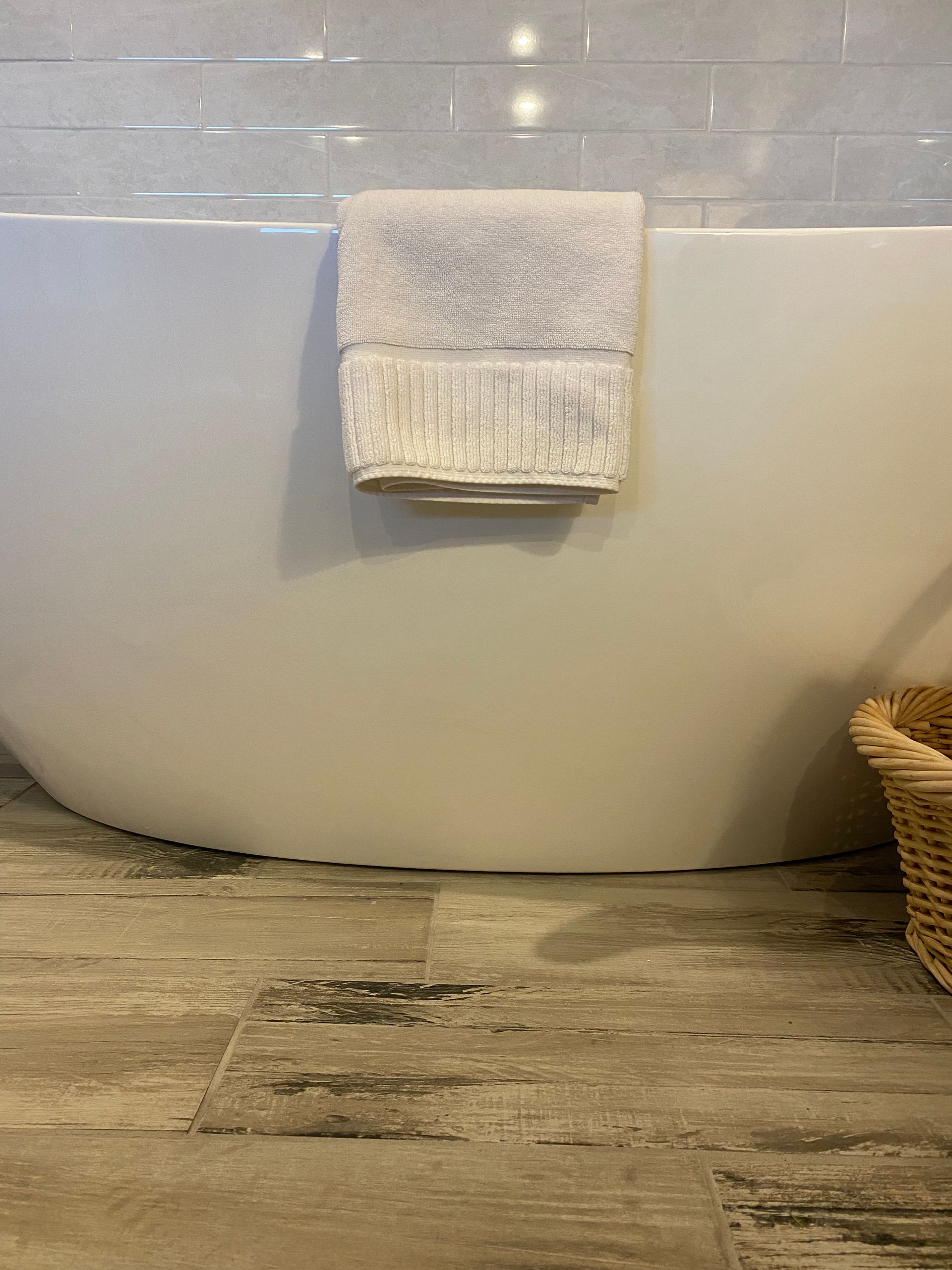 A towel is hanging on the side of a bathtub in a bathroom.