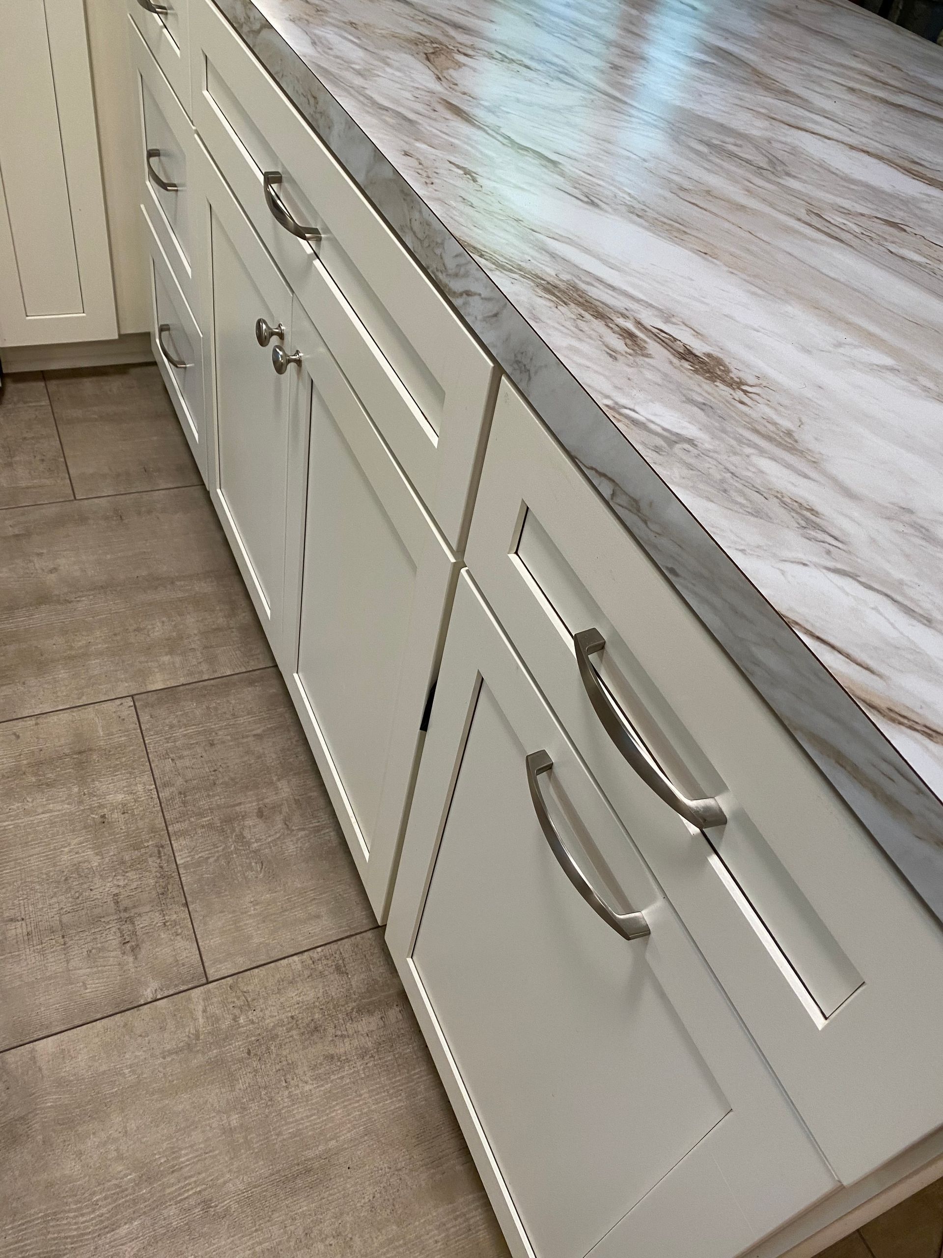 A kitchen with white cabinets and a marble counter top