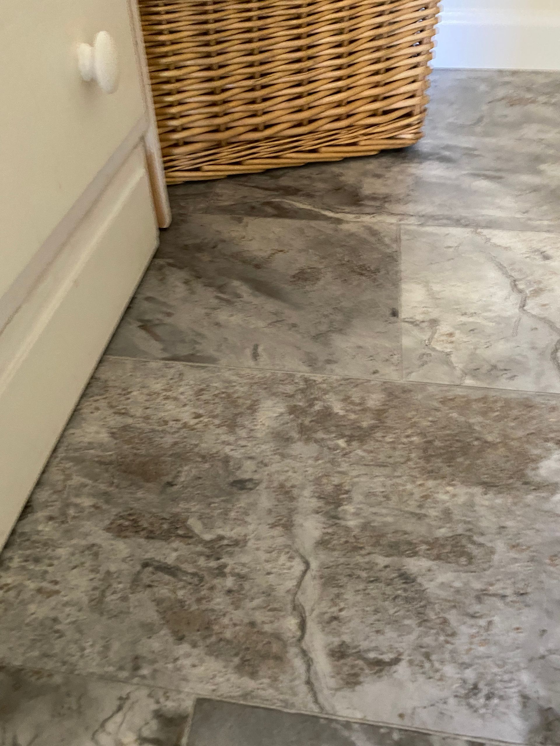 A close up of a tiled floor next to a wicker basket.