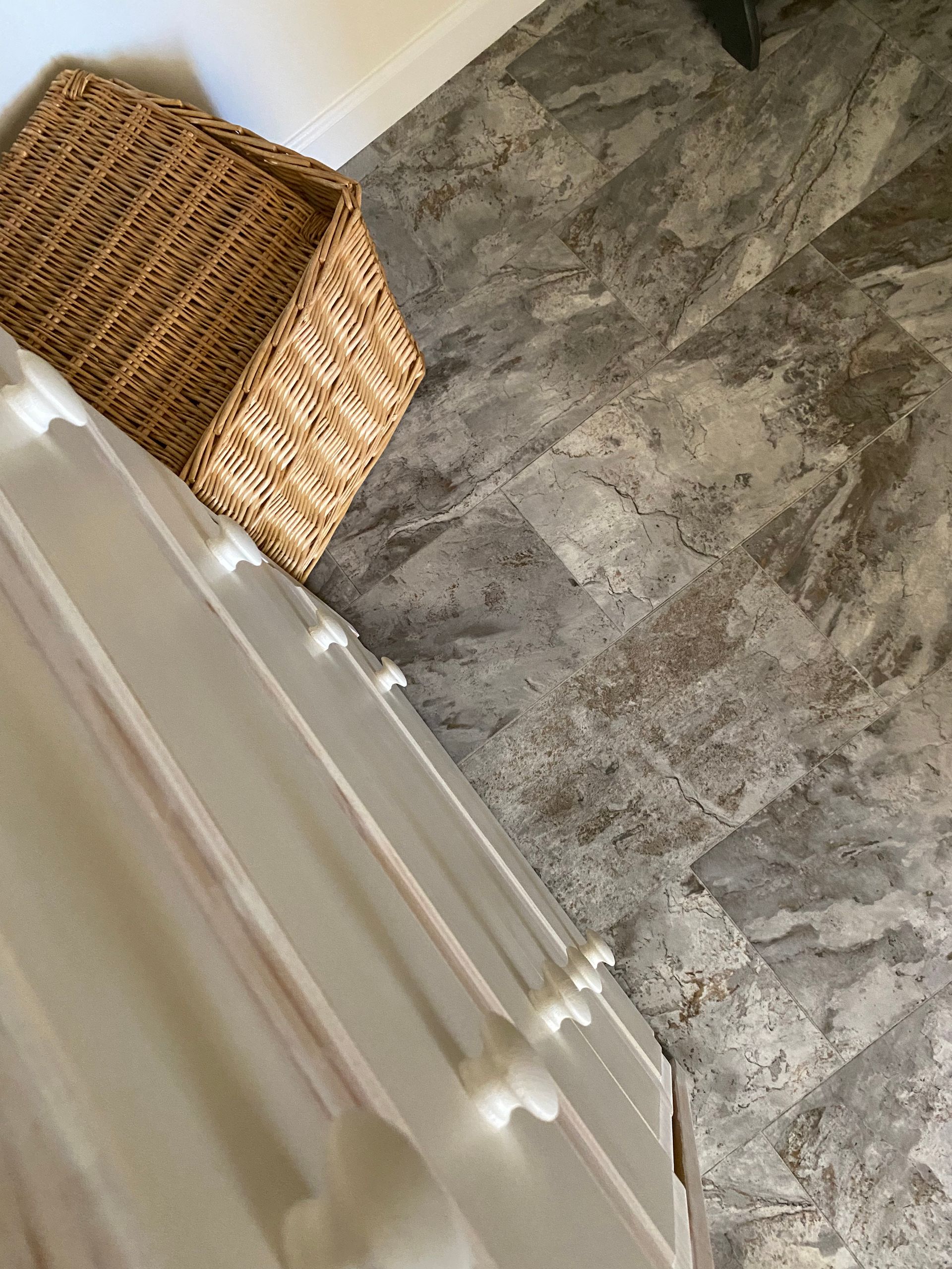 A wicker basket is sitting on the floor next to a dresser.