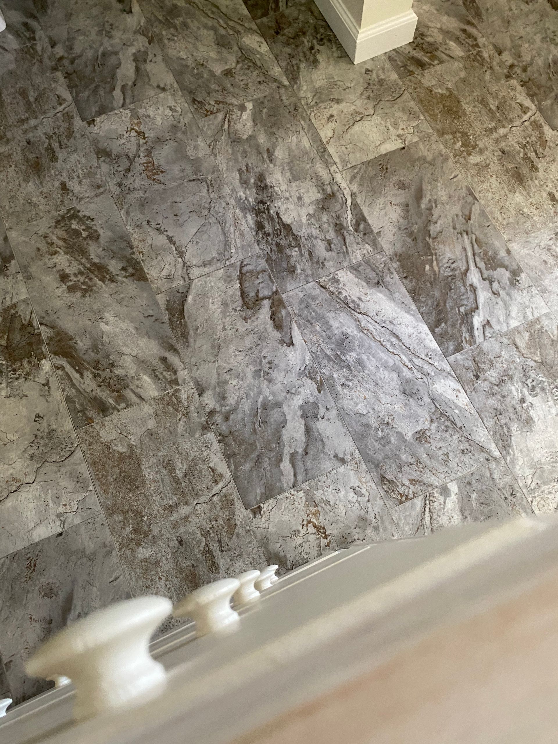 A close up of a marble floor with a staircase in the background.