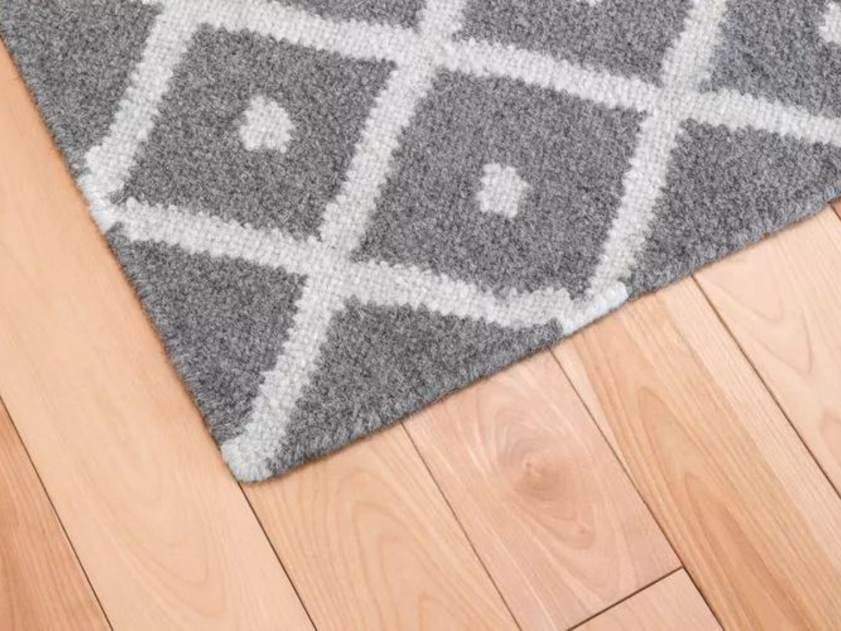 A gray and white rug is on a wooden floor.