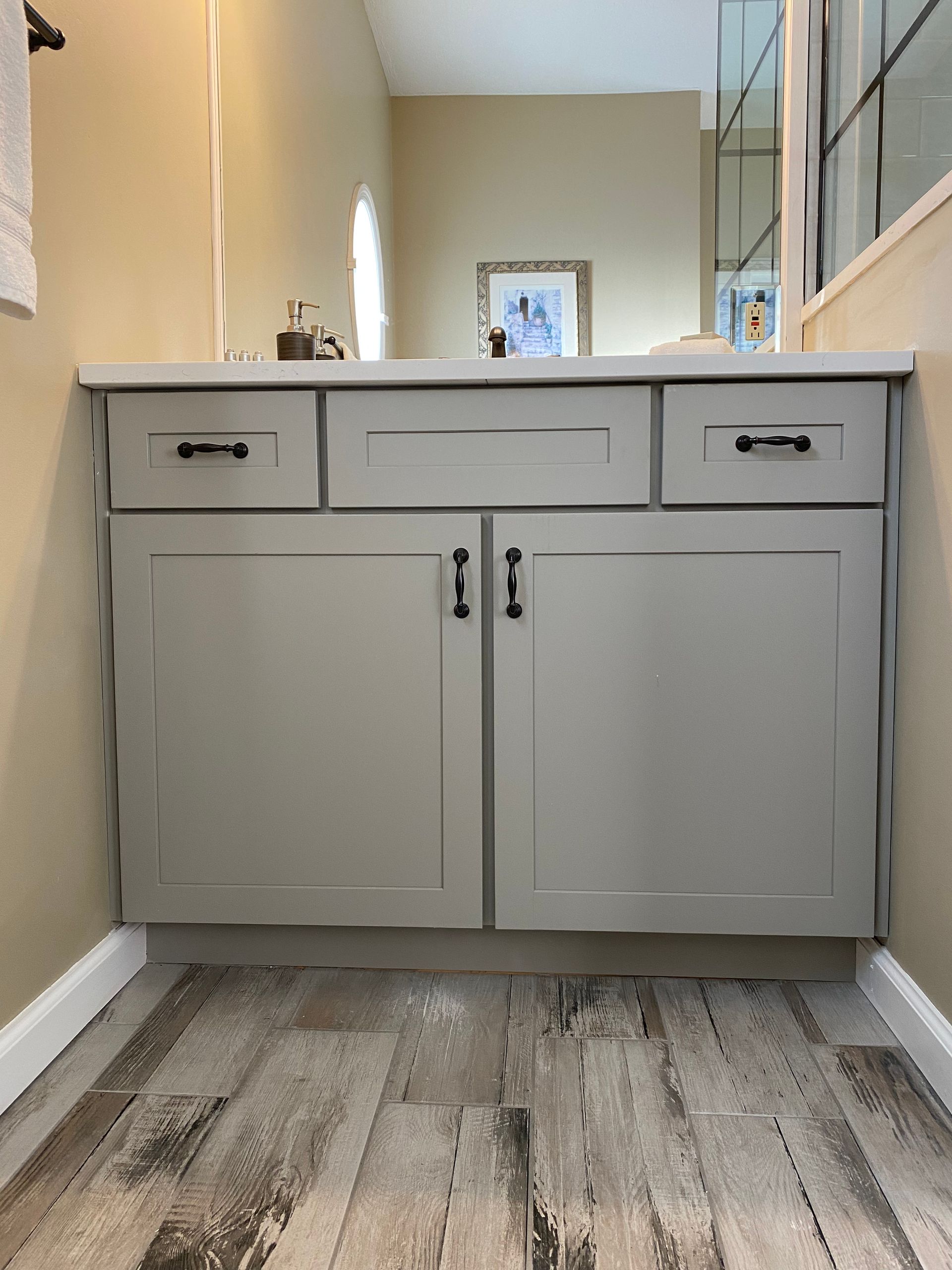 A bathroom with a sink , cabinets , drawers and a mirror.